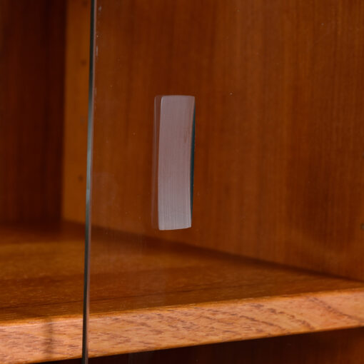 Recessed glass pulls on door of Danish teak china cabinet