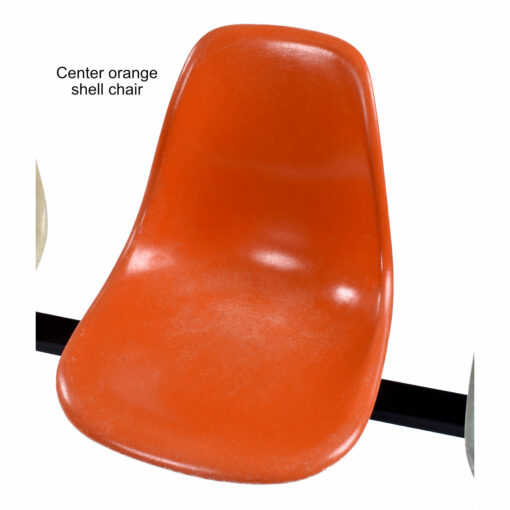 Center orange Eames fiberglass shell chair has some color fading on seat